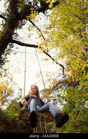 Garçon assis sur une balançoire dans le jardin, au Danemark Banque D'Images