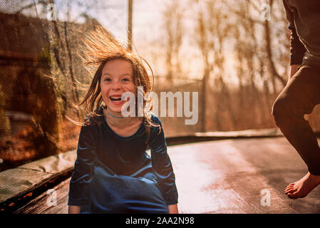 Smiling girl sur un trampoline avec son frère, USA Banque D'Images