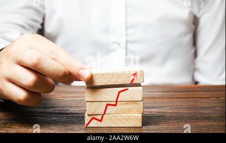 Un homme met en place les blocs avec une flèche rouge graphique. Bâtir une entreprise et d'accroître leurs profits, à réussir. Stratégie et tactique. Le concept de Banque D'Images