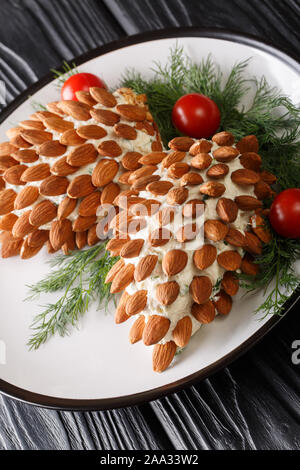 Belle salade de fromage de Noël aux amandes en forme de cônes sur une plaque verticale sur la table. Banque D'Images