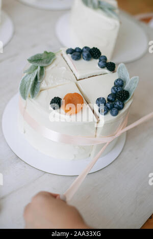 Femme attachant ensemble quatre tranches de gâteau à faire un gâteau composé Banque D'Images