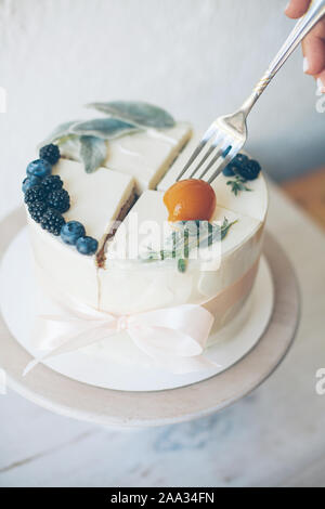 Woman eating peach le dessus d'un gâteau avec glaçage buttercream et fruits Banque D'Images