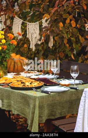 Beau dîner de fête dans le jardin parmi les feuilles d'automne et de citrouilles avec du vin et des tartes. Jour de Thanksgiving concept. Banque D'Images