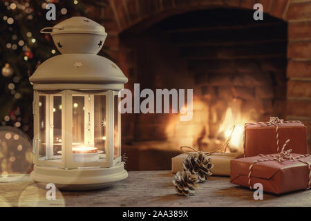 Lanterne avec une bougie allumée, de cadeaux sur une table en bois dans une pièce avec un arbre de Noël et une cheminée la veille de Noël. Banque D'Images