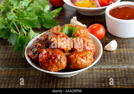 En boulettes frites bol blanc, le persil et la sauce tomate sur une table en bois Banque D'Images