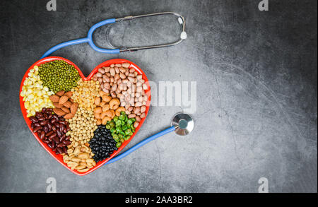 Les différents grains entiers et les légumineuses haricots graines de lentilles et de noix sur fond coloré rouge coeur / Collage divers haricots pois mélange l'agriculture de natur Banque D'Images
