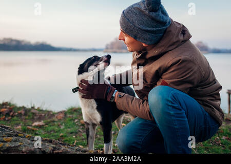 Man Walking dog in autumn park par lac. Heureux animal de s'amuser en plein air Banque D'Images