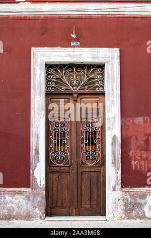 Vieille porte en bois d'un bâtiment peint en rouge, à Mérida, Mexique Banque D'Images