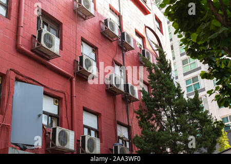 Immeuble de grande hauteur de la cour. La façade est faite de tuiles rouges, une porte en fer, un tuyau et fils dépasser. Climatisation sur le mur. Banque D'Images