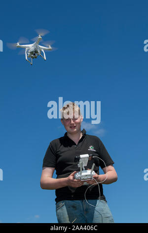 Teenage boy l'exploitation d'un drone DJI dans un cadre rural, Cumbria, Royaume-Uni. Banque D'Images