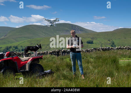 Teenage boy l'exploitation d'un drone DJI dans un cadre rural, Cumbria, Royaume-Uni. Banque D'Images