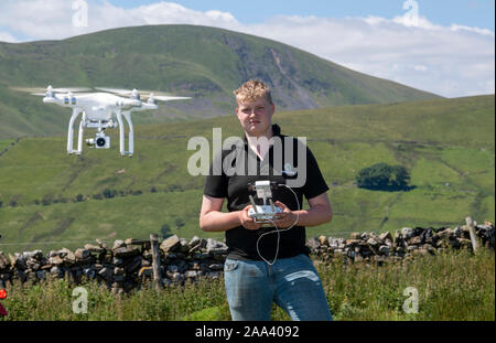 Teenage boy l'exploitation d'un drone DJI dans un cadre rural, Cumbria, Royaume-Uni. Banque D'Images