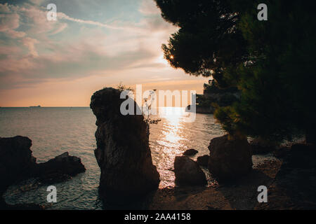 Vue spectaculaire sur la mer Méditerranée côte à Trieste en Italie alors que le coucher du soleil, avec le château de Miramare (Castello di miramare) dans l'arrière-plan. Banque D'Images