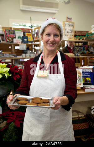 Une femme employée dans un magasin proposant des cookies pour shoppers Banque D'Images