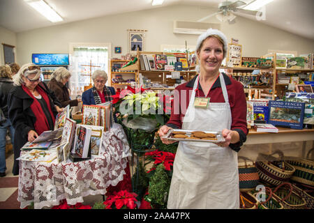 Une femme employée dans un magasin proposant des cookies pour shoppers Banque D'Images