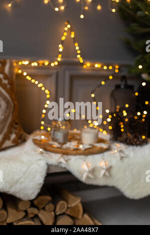 Photo floue de bac avec pot de lait et mug mis sur banc à côté de garland star et l'oreiller. Banque D'Images