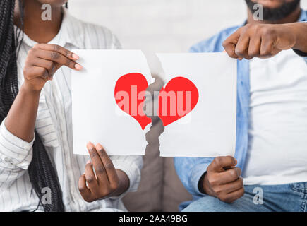 Black couple déchirant le papier avec le symbole de coeur rouge en moitiés Banque D'Images