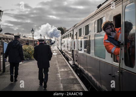 Vue arrière du personnel marchant le long de la plate-forme à la gare d'époque de Kidderminster, départ tôt le matin, chemin de fer à vapeur du patrimoine Severn Valley, Royaume-Uni. Banque D'Images