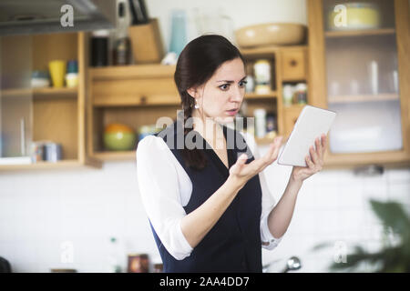 Femme debout dans la cuisine vidéo-conférence Banque D'Images