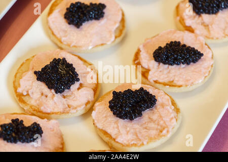 Blinis de tarama et œufs de poisson forfaitaires noir sur un plat Banque D'Images