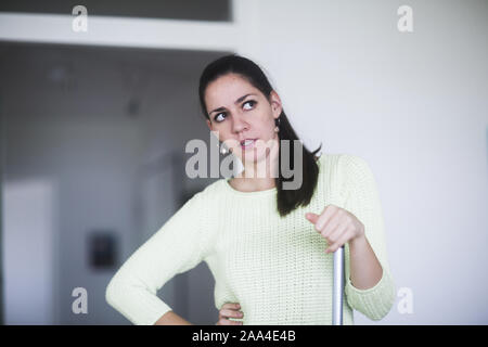 Frustrated woman leaning on a broom Banque D'Images