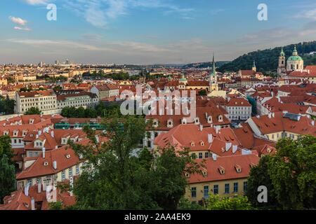 Prague, République tchèque - 20 juillet 2019 - Vue sur les toits rouges, paysage urbain avec des églises et bâtiments historiques. Soirée bleu ciel avec des nuages. Banque D'Images