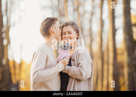 Couple aimant les câlins dans des chandails lumineux chien nain tenant dans leurs mains.Concept Enfants. Banque D'Images