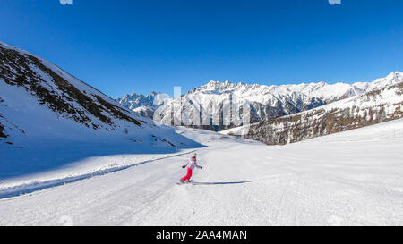 Un snowboarder en descendant la pente à Heiligenblut, Autriche. Des pistes parfaitement entretenues. De hautes montagnes entourant l'homme portant un pantalon jaune et Banque D'Images