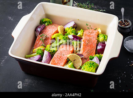 Le saumon, le brocoli et les tranches d'oignons rouges sont préparés dans un plat allant au four. Banque D'Images