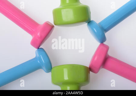 Régime de santé et de remise en forme de symboles. Barres de couleurs différentes mises en motif de cercles, vue du dessus. Mettre en place la forme et sport concept. Les haltères en bleu, rose et vert sur fond blanc en plastique Banque D'Images