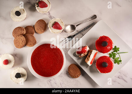 Vue de dessus de crème glacée trempée dans une sauce aux fraises et accompagnés de sauce aux fraises fait maison, biscuits, framboises, mûres et clo Banque D'Images