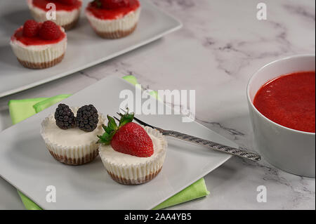 Vue frontale de deux gâteaux faits maison décorée avec des fraises et la moitié d'un terminal blackberry et accompagnés de sauce aux fraises fait maison et Banque D'Images