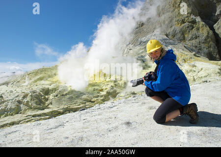 Smiling woman taking a photo de White Island, volcan de l'Île du Nord, dans la baie de Plenty, Nouvelle-Zélande Banque D'Images