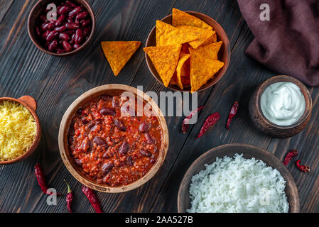 Bol de chili con carne avec garniture sur une table en bois Banque D'Images