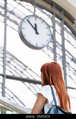 Femme se dresse sur fond flou de l'horloge murale Banque D'Images