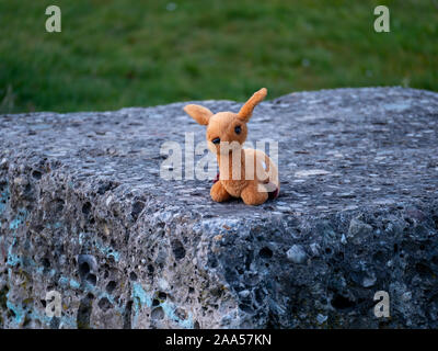 Perdu animal en peluche qui ressemble à un jouet bamby assis sur une pierre Banque D'Images