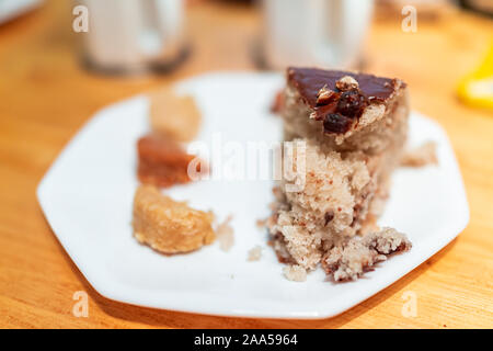 Gros plan du dessert vanille jaune tranche de gâteau fait maison avec du glaçage au chocolat et noix de coco macarons sur table Banque D'Images