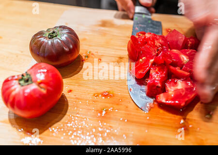 Man chopping vegetables on cutting board tableau dans la cuisine prendre rouge et noir juteux heirloom tomatoes avec la couleur vibrante de jardin Banque D'Images