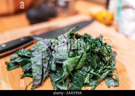 Planche à découper avec des feuilles de chou rouge vert haché dans la cuisine les légumes pour la préparation des repas et le couteau en arrière-plan Banque D'Images