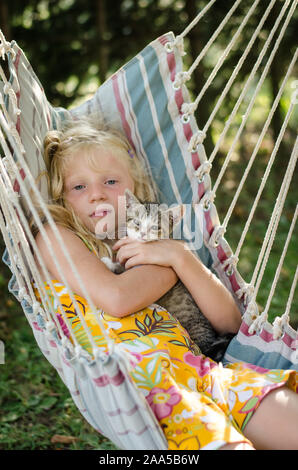 Jolie fille en hamac avoir bon temps avec chat mignon dans un beau jour d'été ensoleillé Banque D'Images