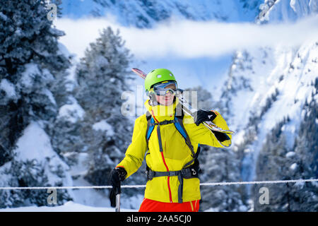 Portrait de l'homme sportif en casque avec skis sur l'épaule contre l'arrière-plan de montagnes en après-midi Banque D'Images