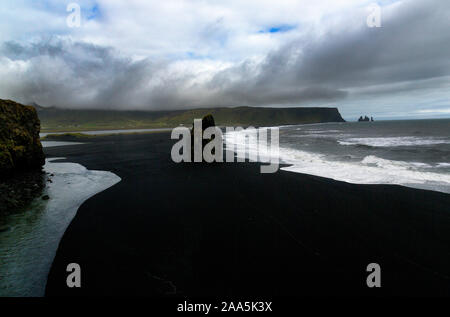 Arnardrangur "Eagle Rock' en arrière-plan Reynisdragar rock formations à la plage de sable noir Reynisfjara qui jouit de la côte de l'Océan atlantique près du village de Vik, Banque D'Images