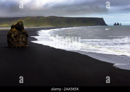 Arnardrangur "Eagle Rock' en arrière-plan Reynisdragar rock formations à la plage de sable noir Reynisfjara qui jouit de la côte de l'Océan atlantique près du village de Vik, Banque D'Images