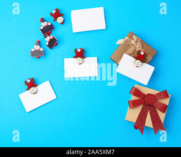Boîtes avec des arcs rouge blanc et vide, cartes d'affaires et de pinces à linge décoratif sur un fond bleu, vue du dessus Banque D'Images