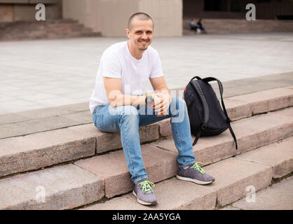 L'homme à la caméra en souriant et en étant assis sur des escaliers Banque D'Images