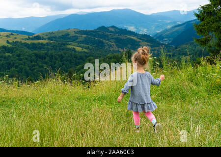 Petite fille debout dos à l'appareil photo avec une vue sur la montagne Banque D'Images