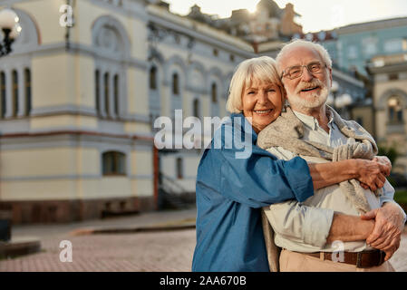 L'amour vrai n'a pas de date d'expiration. Portrait of smiling senior woman in casual clothing enlacés et looking at camera avec sourire tout en st Banque D'Images