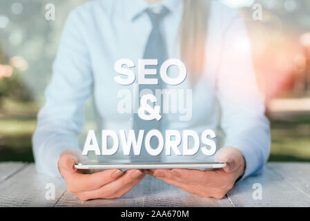 Texte de l'écriture l'écriture Seo et Adwords. Photo conceptuelle payer par clic marketing numérique Google Adsense Female business personne assise par table et Banque D'Images