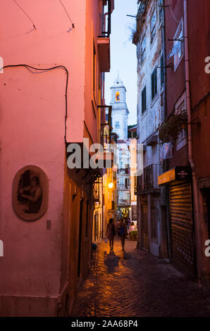 Lisbonne, Portugal : deux femmes marcher la nuit sur une ruelle pittoresque de l'Alfama, le plus vieux quartier de Lisbonne. Santo Estevao clocher en arrière-plan Banque D'Images