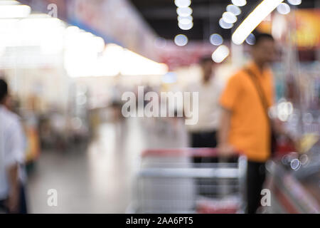 Résumé de l'allée de supermarché floue avec des étagères et méconnaissable les clients comme arrière-plan. Banque D'Images